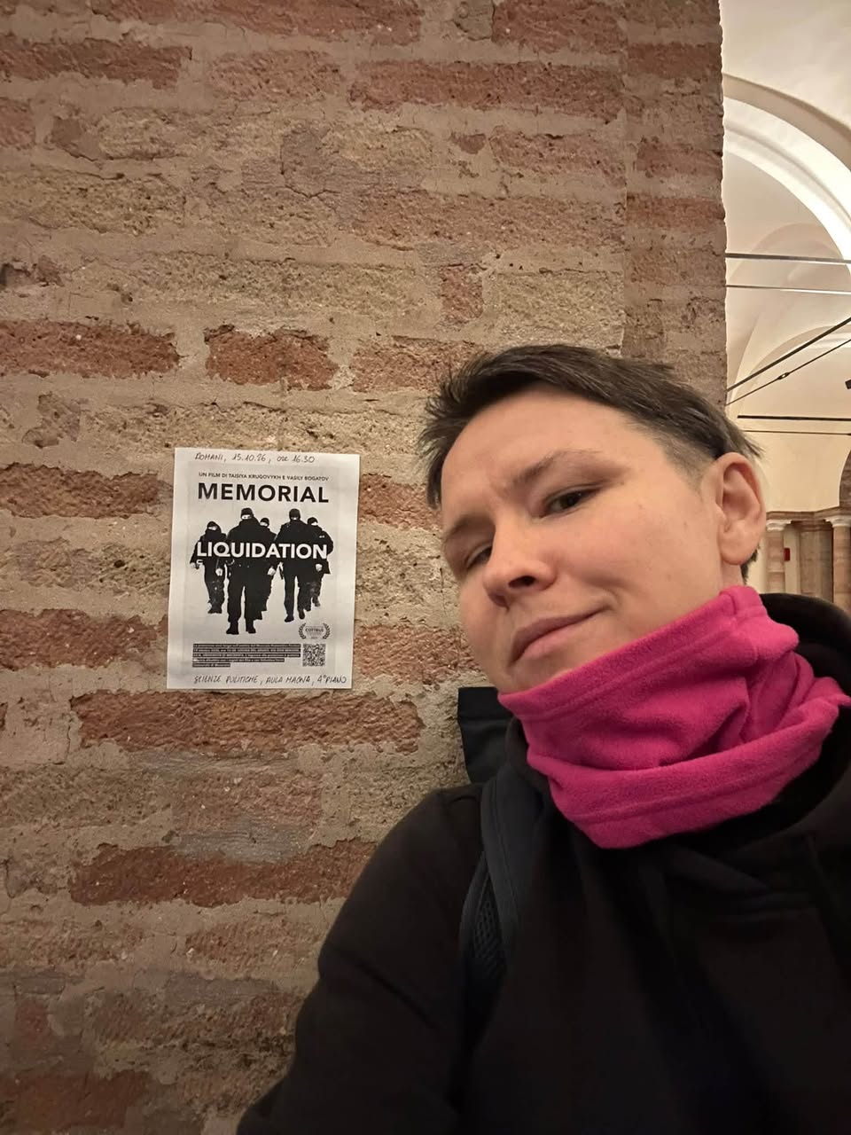 A participant beside the screening poster in Macerata