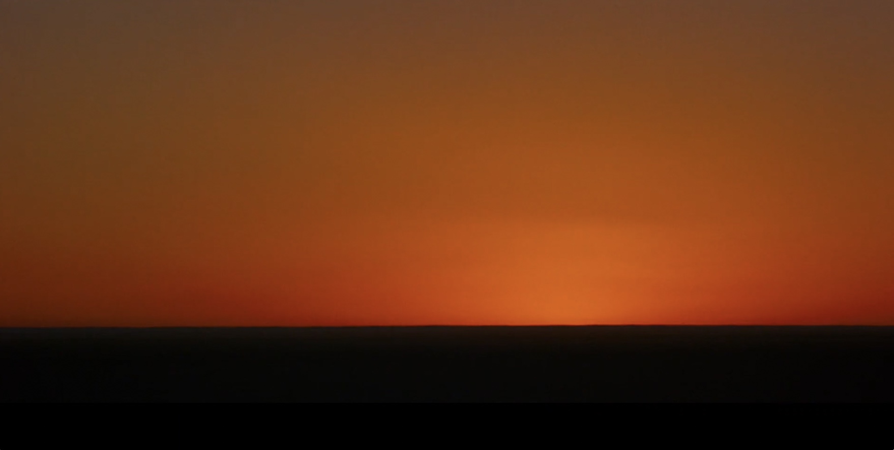 Orange sky over a dark desert horizon